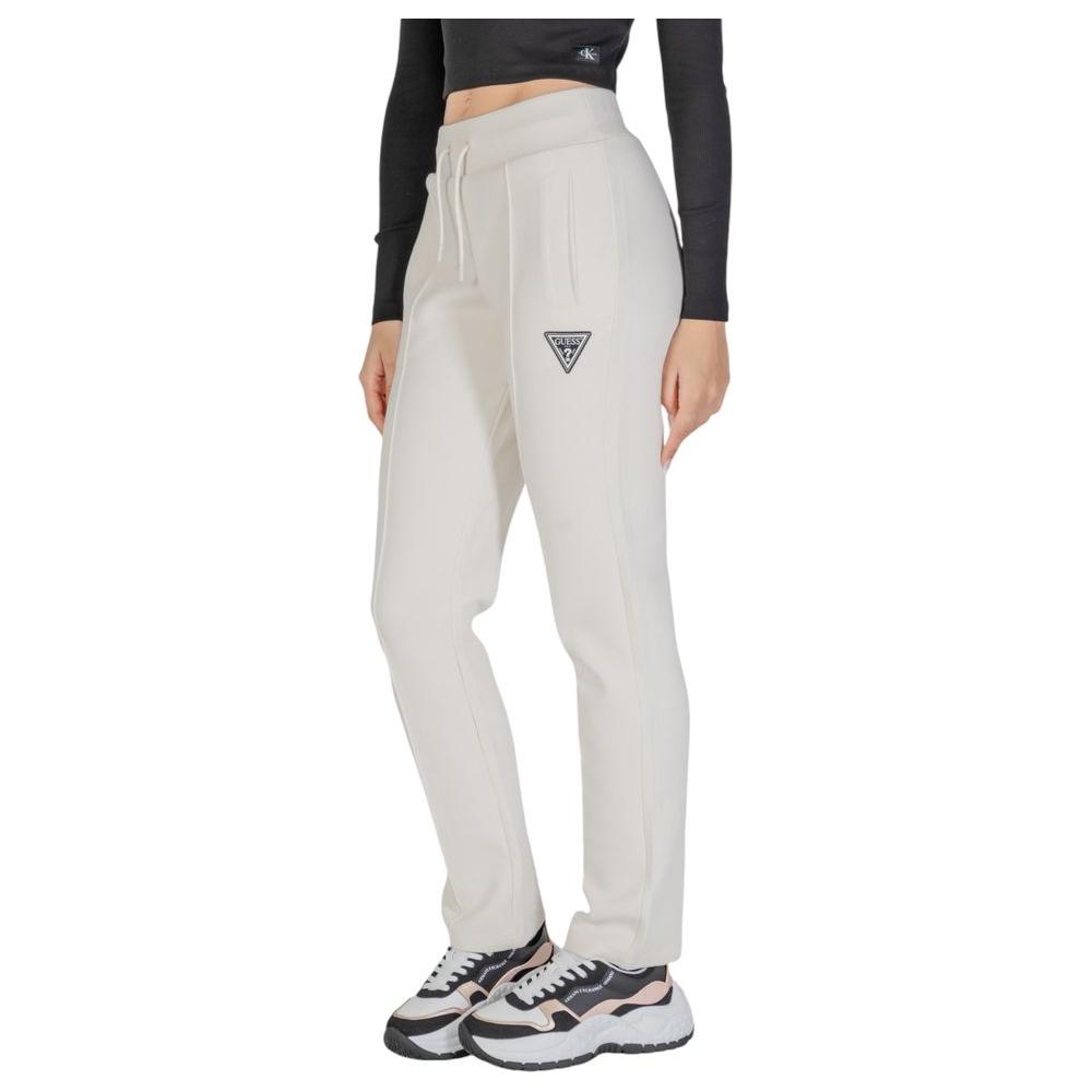 Woman wearing Guess Active cream cotton jeans with straight leg design and logo, showcasing gym or casual wear style.