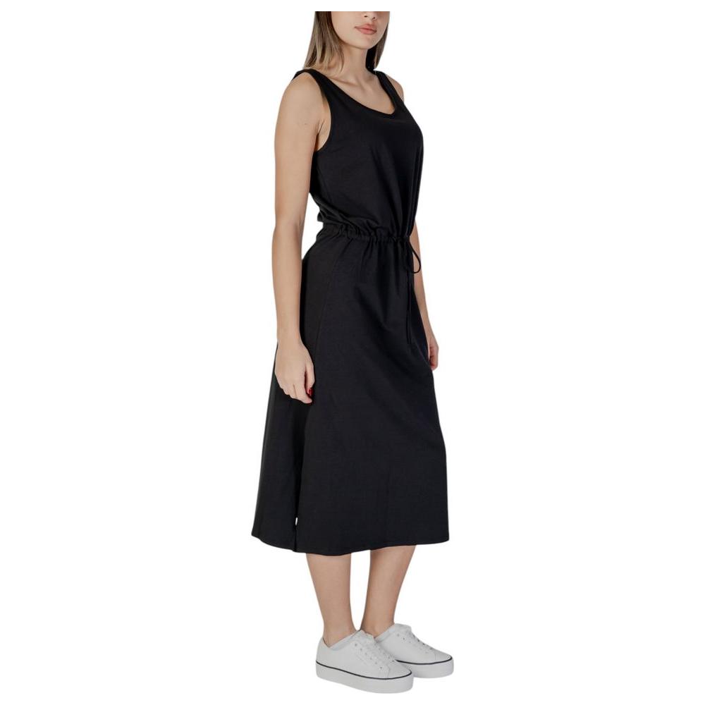 B.Young black cotton dress, sleeveless, women's spring/summer collection, side view, paired with white sneakers.