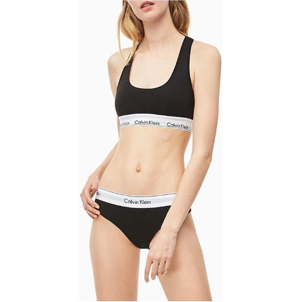 Woman wearing Calvin Klein black cotton underwear set with branded elastic band, featuring a minimalist sporty design and comfortable fit.