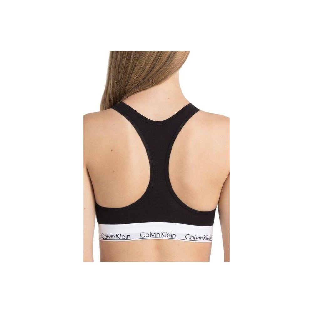 Woman wearing Calvin Klein black cotton underwear bra, featuring sporty design and elastic band with logo, back view.