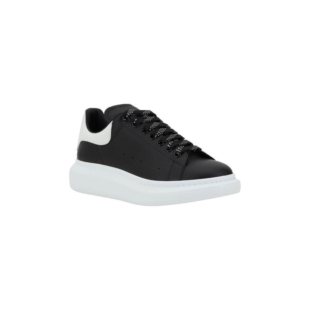 Black and white Alexander McQueen leather sneakers with lace-up closure and platform sole, showcasing contemporary elegance and bold design.
