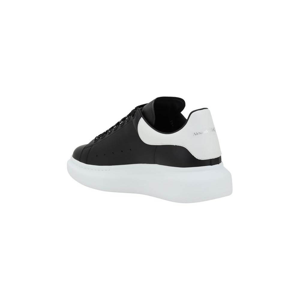 Black and white Alexander McQueen leather sneaker with platform sole, featuring a logoed heel and lace-up closure.