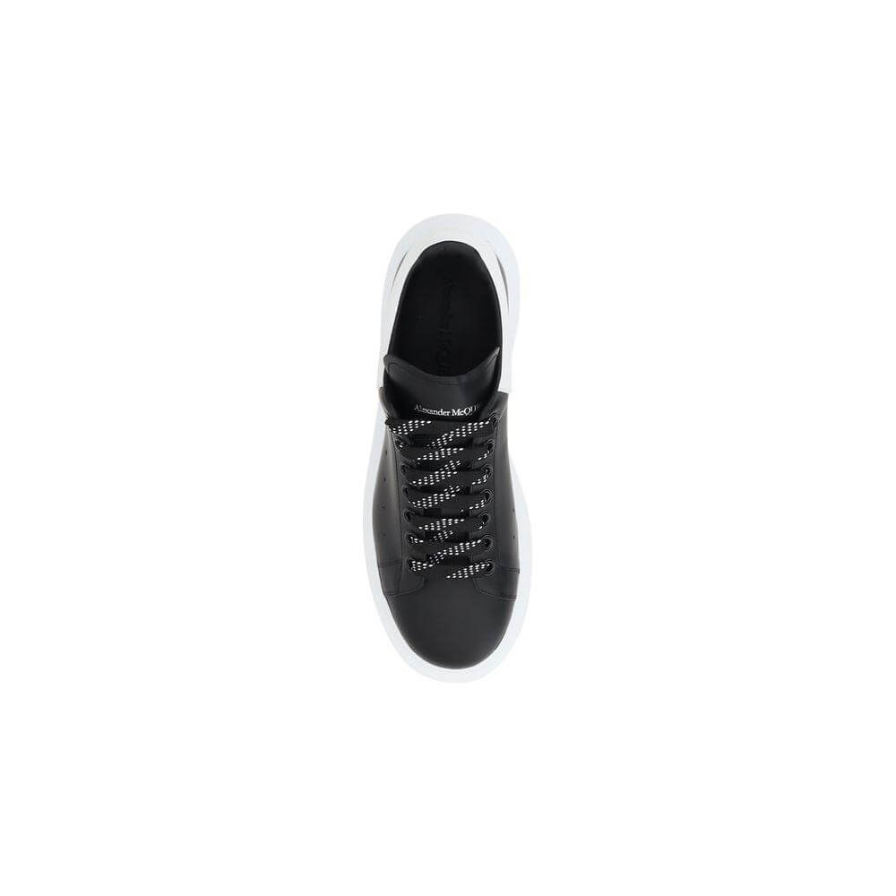 Top view of Alexander McQueen leather sneakers with black front lace-up closure and white platform sole, showcasing iconic design details.
