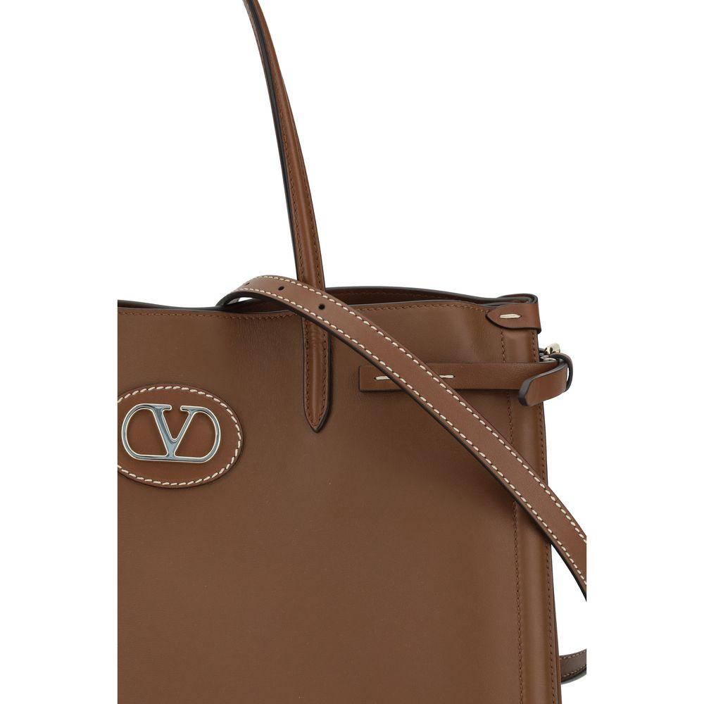 Valentino Garavani Antibes handbag with side buckles and metallic logo embellishment, showcasing luxurious gold finish accents.