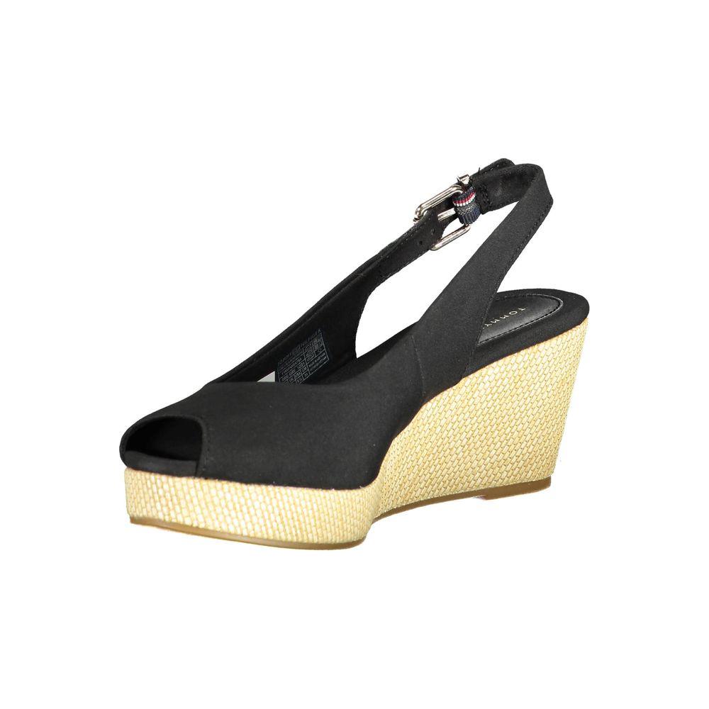 Tommy Hilfiger black leather sandal with ankle buckle and wedge heel, featuring contrasting details and iconic logo for fashion-forward style.