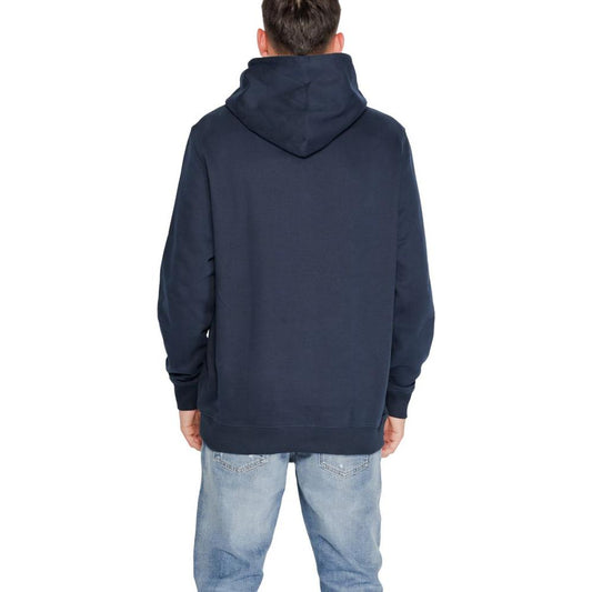 Back view of a man wearing a blue Tommy Hilfiger cotton sweater from the fall/winter collection, paired with light blue jeans.