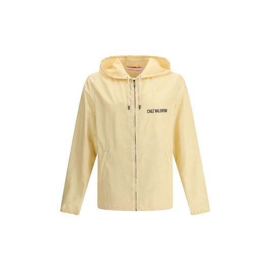 Valentino waterproof jacket with hood, front zipper, side pockets, and logo on front and back in light yellow.